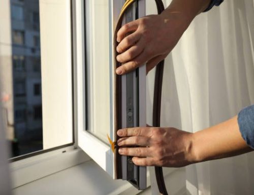 Construction worker putting sealing foam tape on window, closeup